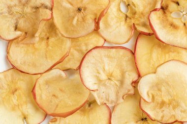 Arka plan olarak beyaz plaka üzerinde yakın çekim doğal kurutulmuş elma cipsi.