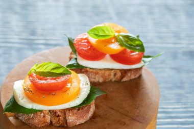 Yuvarlak iki bruschettas Caprese gri ahşap masada kesilmiş testere.