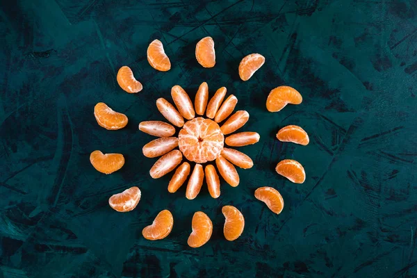 Bovenaanzicht van geschilde mandarijnen, aangelegd in cirkel in het midden van de heldere Smaragd groene achtergrond. — Stockfoto