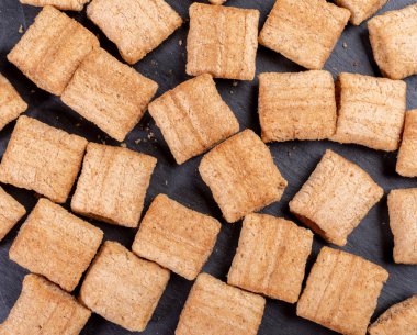 Koyu gri şist arka plan üzerinde gevrek kare buğday yastıklar. 