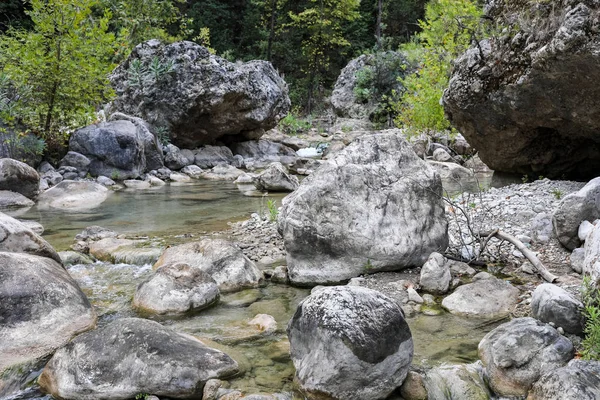 Piccolo fiume che scorre tra la foresta tra grandi massi di pietra . — Foto Stock