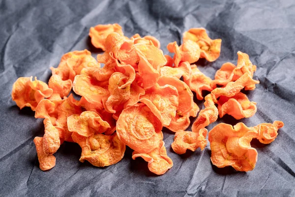 구불 구불 한 검은 포장지에 오렌지 당근 칩의 작은 더미. — 스톡 사진