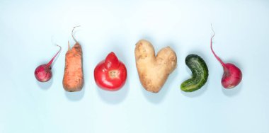 Six ripe ugly vegetables: potato, tomato, cucumber and radish laid out in row on light blue background.  clipart