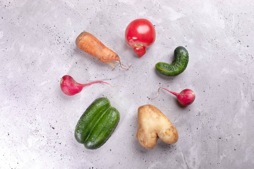 Set of ugly vegetables laid out in circle on concrete background. 