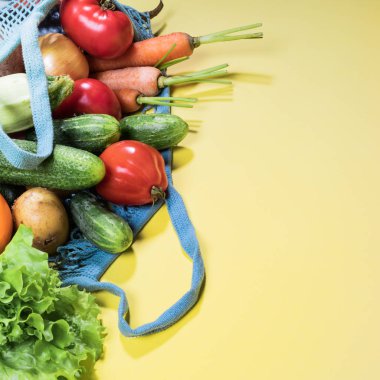 Kopya alanı ile sarı arka plan üzerinde taze çiftlik sebze ile Mesh alışveriş çantası. Kare atış. 