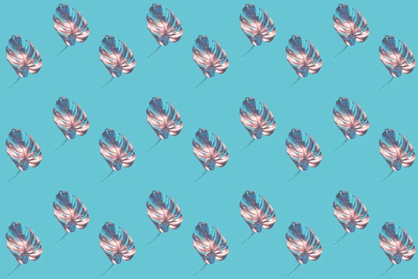 Creative pattern of diagonally laid out colored by bronze with blue monstera leaves on trendy blue background. — ストック写真