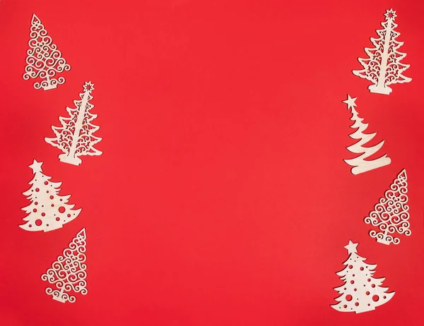 Maqueta de Navidad con dos filas verticales de decoraciones de madera bricolaje árboles de Navidad sobre fondo rojo con espacio para copiar . — Foto de Stock