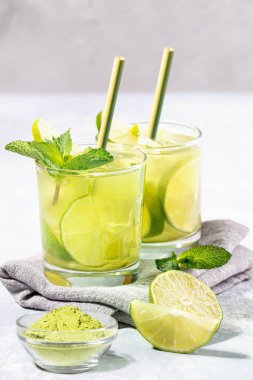 İki bardak kireç, buz, nane şekeri, kibrit tozu ve açık gri arka planda kamış içen bambu pipetli buzlu kibrit çayı. Sağlıklı yiyecek, plastik yok, ziyan yok. Dikey çekim. Seçici odak.