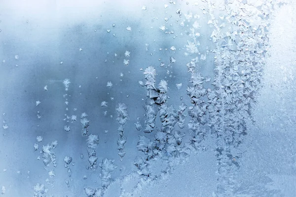 Schöne gefrorene Muster von vertikalen Reihen von gefrorenen Schneeflocken auf eisigen weißen Fensterscheiben. — Stockfoto