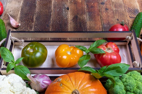 Три барвисті фермерські помідори в маленькій коробці та овочі на старому сільському стилі старовинний дерев'яний стіл крупним планом . — стокове фото