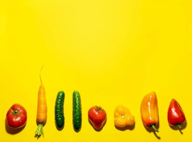 Açık sarı arka planda sıralanmış taze çiftlik sebzeleri. Üst görünüm, alanı kopyala.