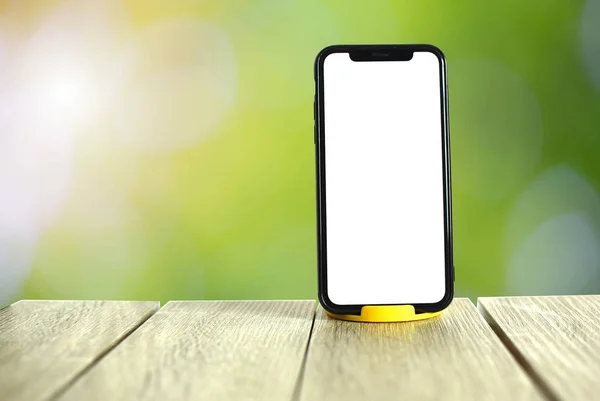 Yeşil arka planda telefon, ahşap zemin