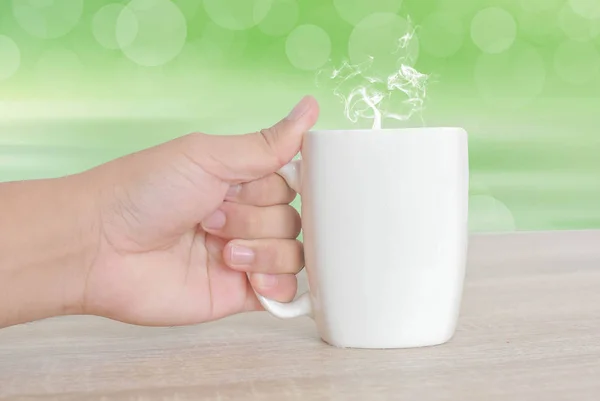 Mão segurando uma xícara de café da manhã em um fundo verde — Fotografia de Stock