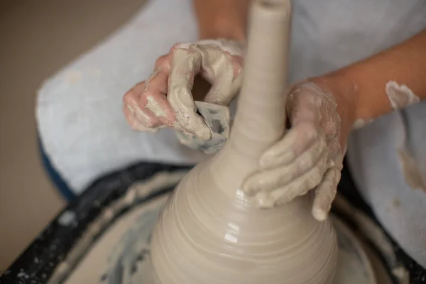 Ceramist przetwarza krawędzie glinianego wazonu obracające się na kole garncarskim — Zdjęcie stockowe