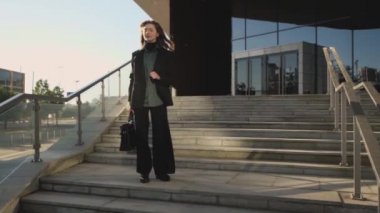 Bir iş kadını büyük bir şirketin merdivenlerinde durup etrafa bakıyor.