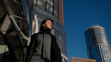 Gülümseyen bir kadın binaların önünde güneşin tadını çıkarmaya gitti.