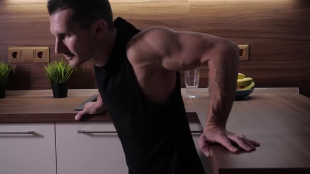 A young handsome athlete is engaged in sports in kitchen during the quarantine — Stock Video