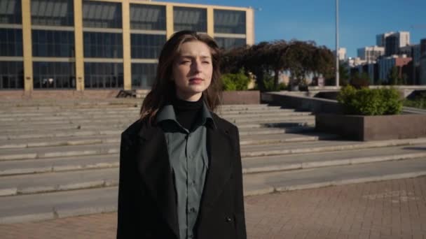 Beautiful natural brunette with dreamy look walks through square on a clear day — Stock Video