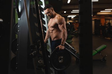 Seksi vücutlu genç bir sporcu spor salonunda poz verir.