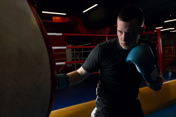 Young muscular man fighter practicing arms with punching bag — Stock Photo, Image