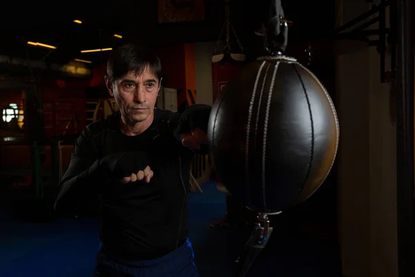 A black-haired middle-aged man in a black rashguard is engaged in boxing — Stock Photo, Image