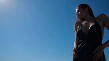 Siyah elbiseli seksi esmer kavurucu güneşin altında güneşleniyor.