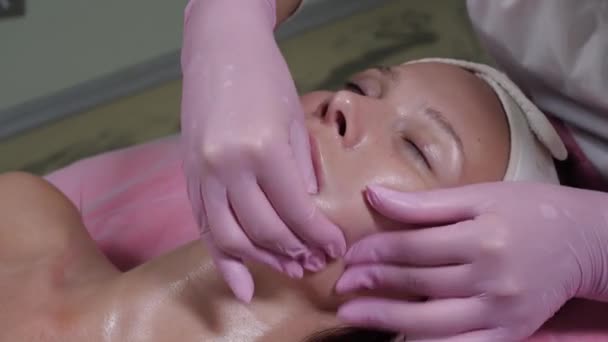 Menina na massagem facial. uma massagem bucal do rosto. Massagem profissional — Vídeo de Stock