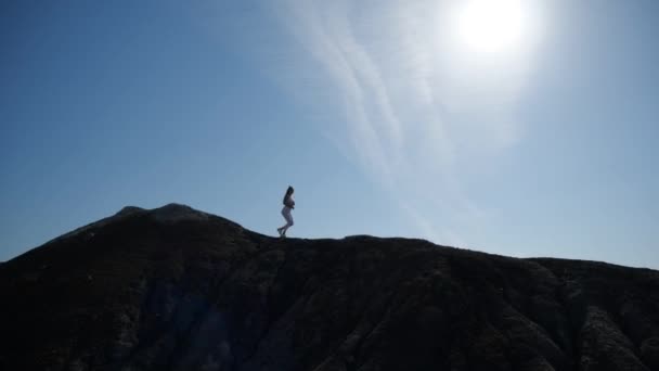 La silueta de una chica corriendo alto en el borde de una colina . — Vídeos de Stock
