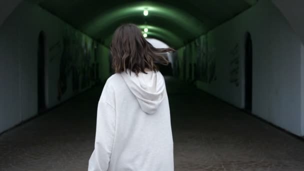 Nettes Mädchen geht in U-Bahn-Tunnel und schaut in Kamera — Stockvideo