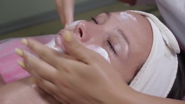 La aplicación de crema en la cara de una niña — Vídeo de stock