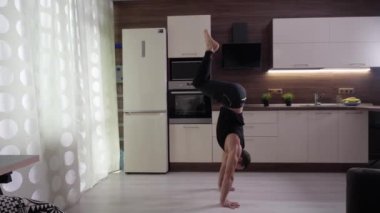 Bir sporcu evde, mutfağın arka planında bir raf yapar.