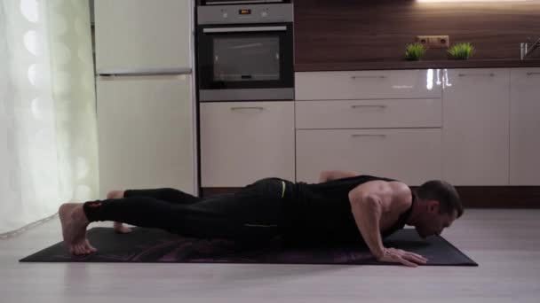 Un hombre hace flexiones alternativamente cambiando de manos. Formación en el hogar . — Vídeos de Stock