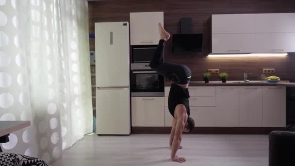 Un atleta hace un estante en sus manos en casa en el fondo de una cocina — Vídeos de Stock