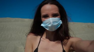 Plajda Coronavirus sırasında maske takan bir kız. Salgın 2020.