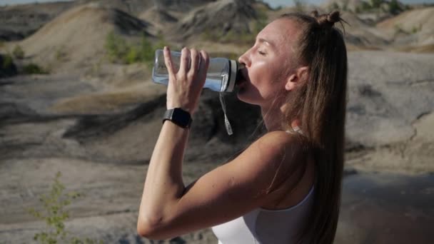 La chica está cansada después del entrenamiento expira y bebe agua y botellas. — Vídeos de Stock