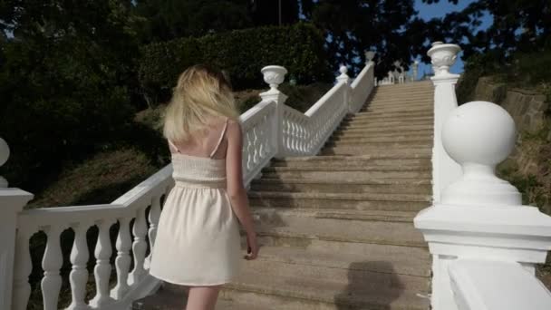 Štíhlá dívka leze po dlouhém bílém žebříku nahoru — Stock video