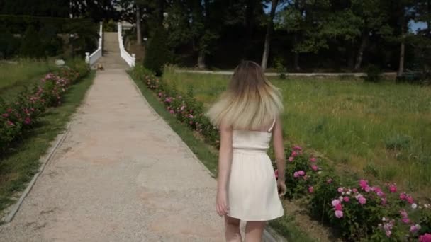 Běžící štíhlá dívka se svěžími vlasy v šatech v parku — Stock video