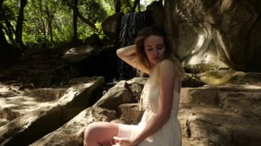 Şelalenin yanındaki beyaz elbiseli tatlı sarışın kız.