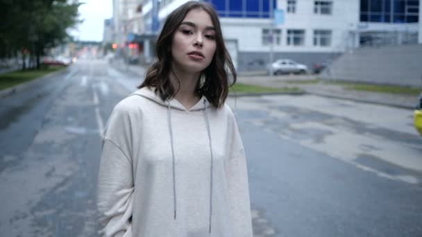 Portret van mooi meisje in een witte hoodie kijkend naar de camera met interesse — Stockvideo