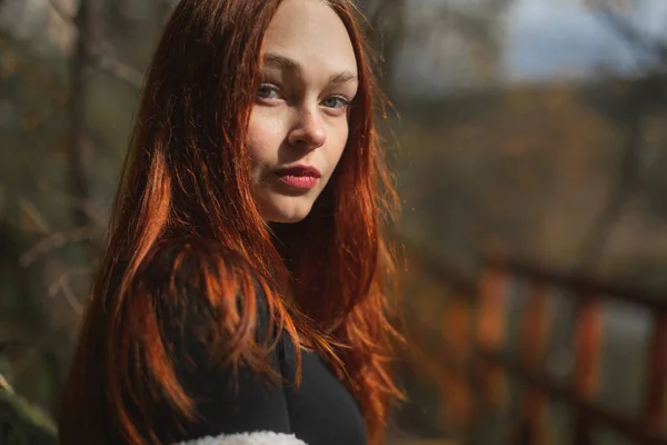 Portret van een roodharig meisje met lang haar kijk naar de camera met een kalme blik — Stockfoto
