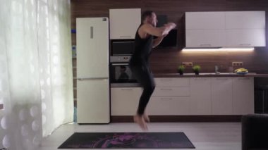 Sporcu zıplar ve dizlerinin üstüne çöker, evde antrenman yapar.