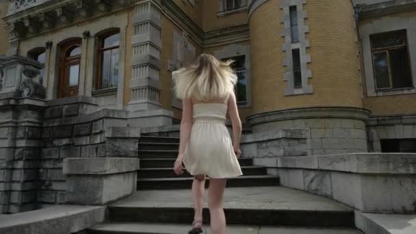 Blonde im Kleid rennt die Treppe zum Gebäude hinauf — Stockvideo