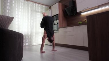 Sporcu, elleri üzerinde bacaklarını kaldıran bir askı sergiliyor.