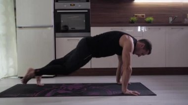 Genç yakışıklı bir atlet mutfakta zor bir egzersiz yapıyor. 