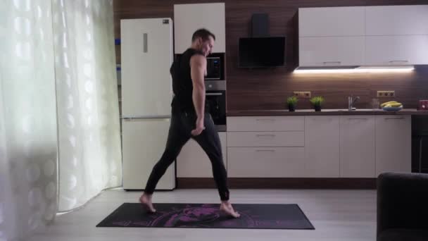 Спортсмен выполняет упражнения на ногах и ягодицах на домашней кухне — стоковое видео