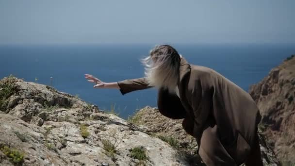 Ein junger Mann mit langen Haaren erreicht die Spitze eines Berges auf der Krim — Stockvideo