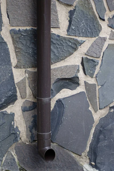 Farklı şekil ve renklerde granit blokların duvarın arka planda su akışı için metal boru kahverengi.