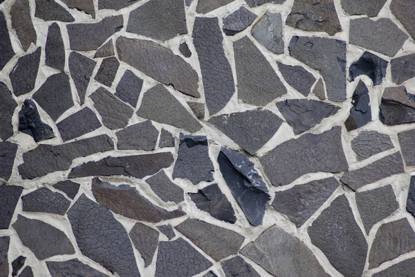 Farklı boyutlarda bazalt bloklar ve aralarında hafif çimento dikişleri Duvar.