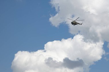 Mavi gökyüzü, beyaz bulutlar ve askeri helikopter. Beyaz bulutlu mavi gökyüzünün arka planında uçan bir helikopter..