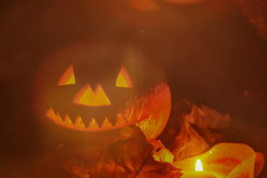 Bulanık arka plan Cadılar Bayramı. Karanlıkta yanan bir mumla Cadılar Bayramı için balkabağından oyulmuş bulanık parlayan bir fener. Çirkin balkabağı surat, kopyalama alanı